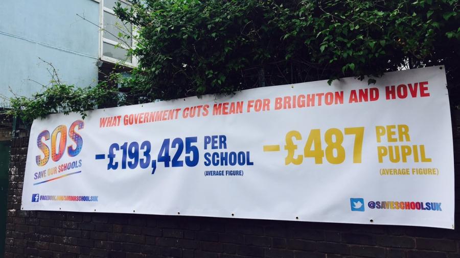 A picture of a banner on a school wall showing figures for funding cuts